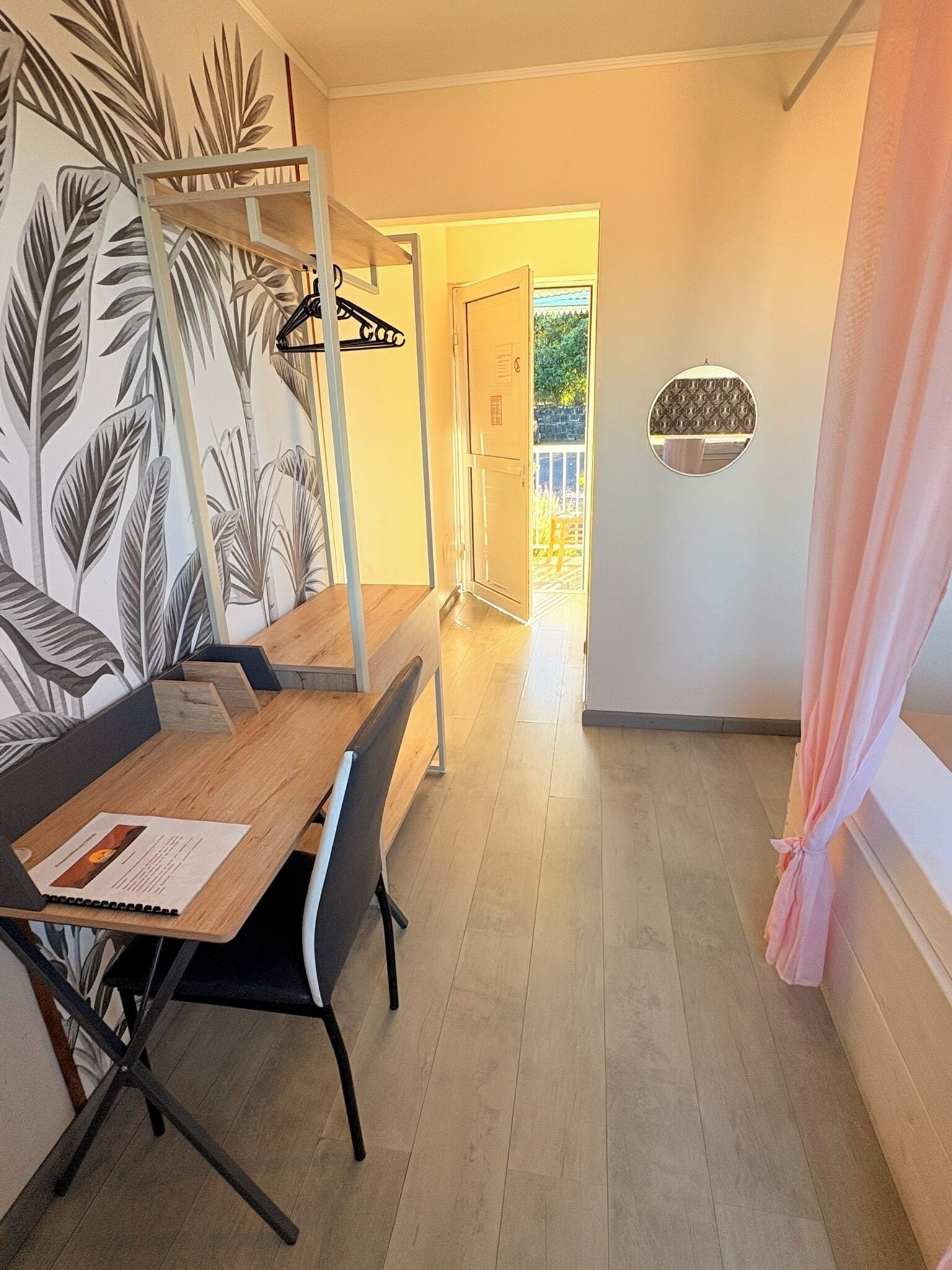 Un coin repas avec une table en bois, des chaises et un mur orné d’un motif de feuilles.