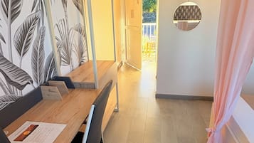Een eethoek met een houten tafel, stoelen en een muur met een bladpatroon.