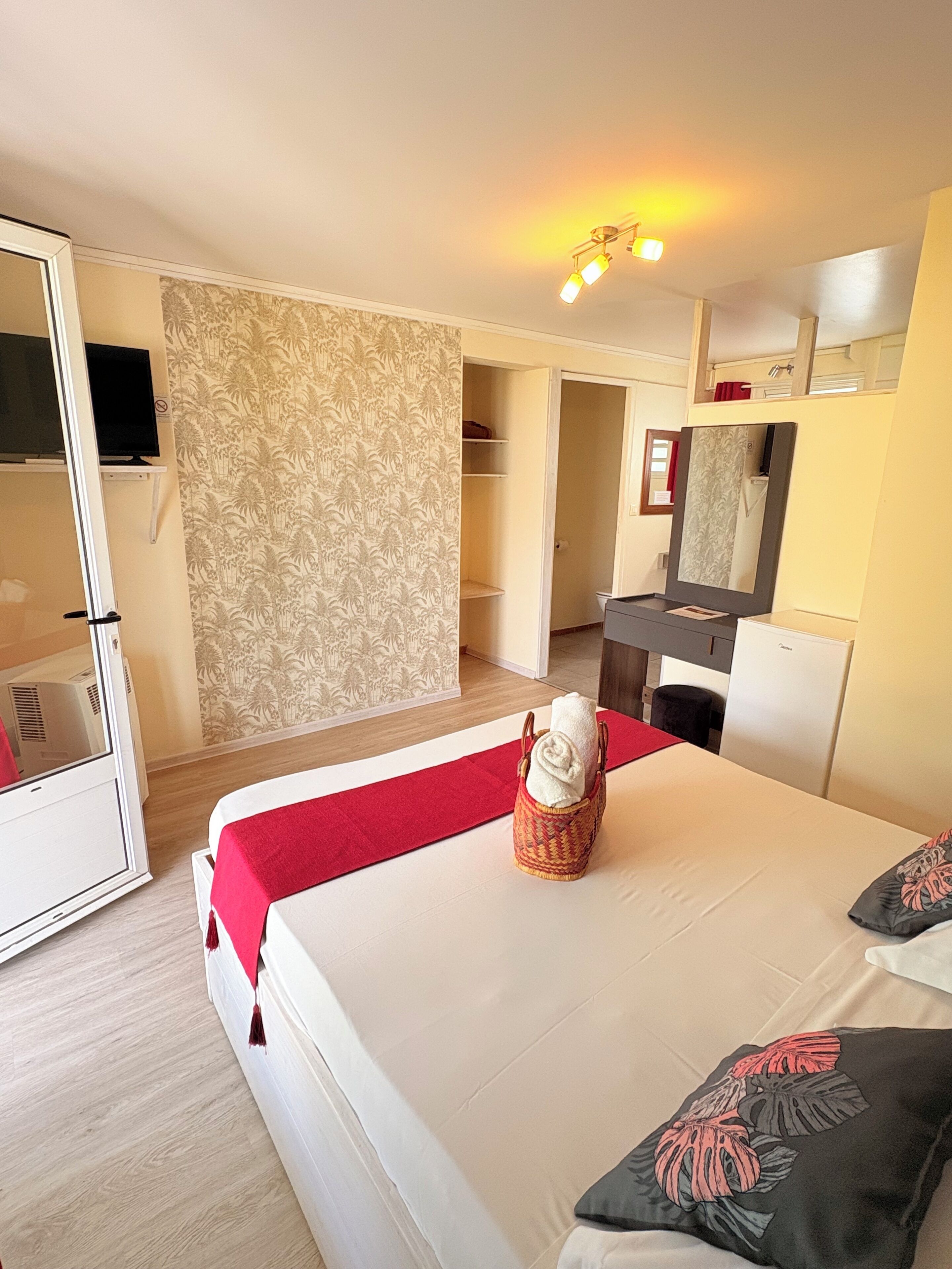 A hotel room with a bed, a desk, a wardrobe, and a bathroom visible through an open door.