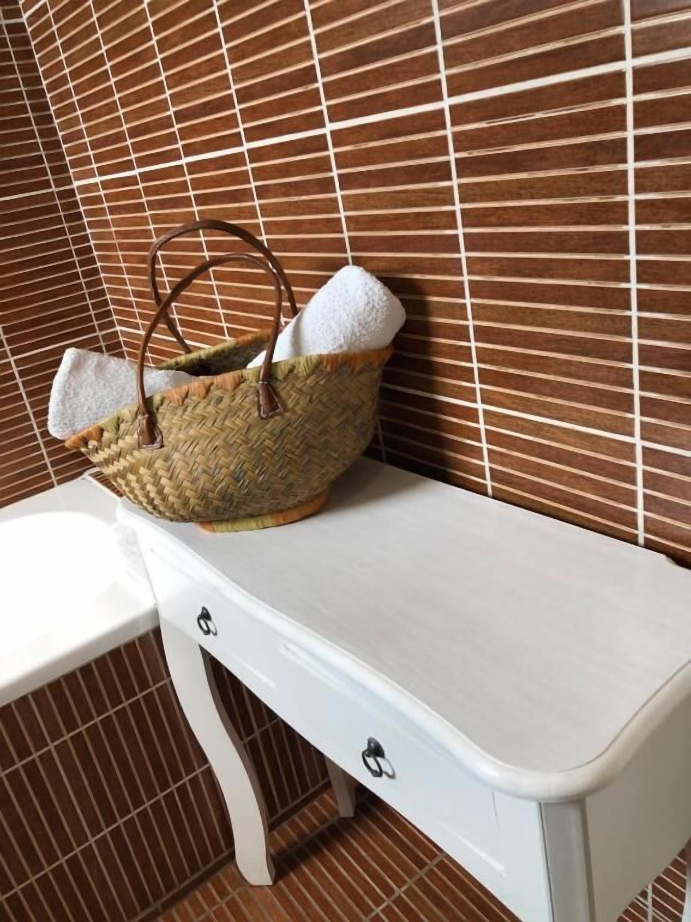 Un banco blanco con una cesta tejida encima.