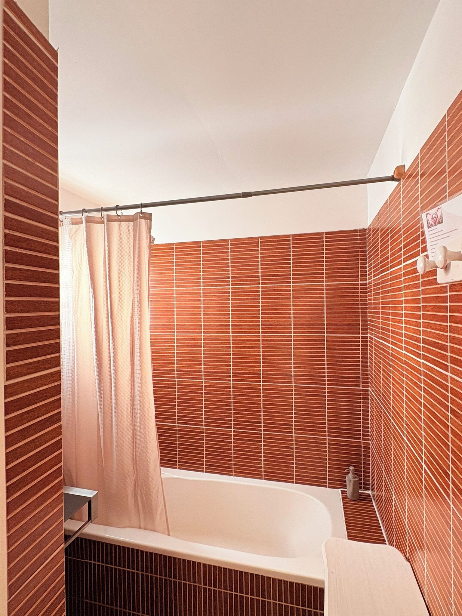 A bathroom with a bathtub, a shower curtain, and a towel rack.
