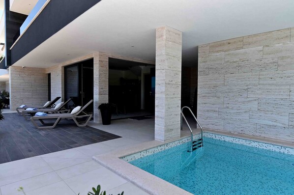 Un espace piscine extérieur moderne, doté de chaises longues et d’une piscine à l’eau d’un bleu cristallin.