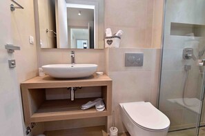 Une salle de bain moderne avec un lavabo blanc, un meuble-lavabo en bois, une cabine de douche en verre et des toilettes.