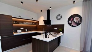 Una cocina moderna con armarios oscuros, una isla central y un reloj fijado a la pared.