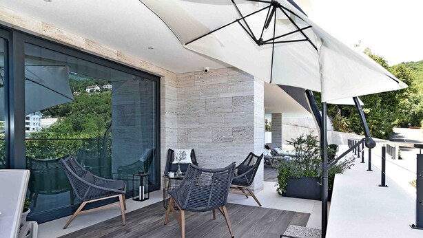 A modern outdoor patio with wicker chairs, a table, and a large umbrella. - Beautiful Villa near centar of town for 4 person B (Icici)