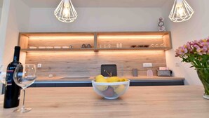 A modern kitchen with wooden shelves, a fruit bowl, and pendant lights. - Beautiful Villa near centar of town for 4 person B (Icici)