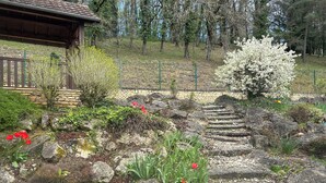 A garden with a stone pathway, red flowers, and a wooden structure. - Gites de Charme 18 Personnes Avec Tennis Dans un Parc de 2 ha . Idéal Familles (Montignac-Lascaux)