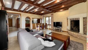 A spacious living room with a fireplace, a television, and a dining area with a kitchen in the background. - Gites de Charme 18 Personnes Avec Tennis Dans un Parc de 2 ha . Idéal Familles (Montignac-Lascaux)
