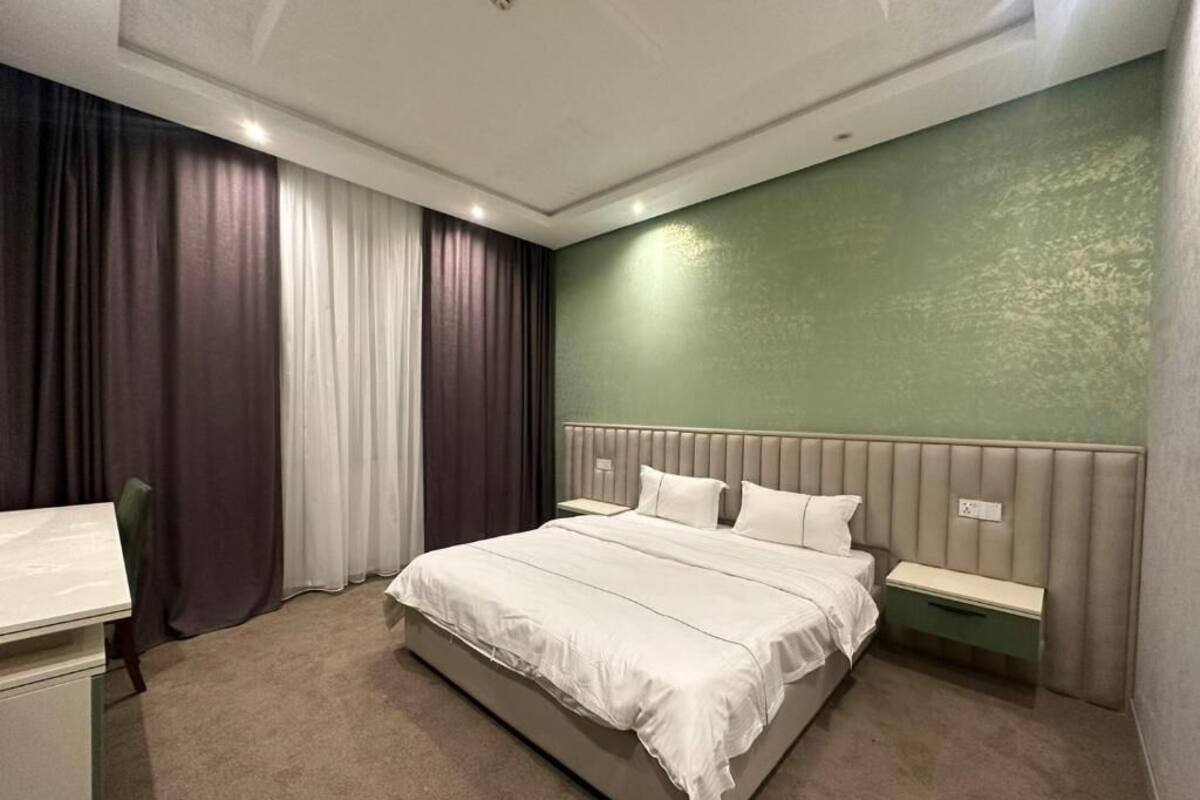 Ein modernes Hotelzimmer mit einem großen Bett, einem Nachttisch, einem Schreibtisch und einem Stuhl.