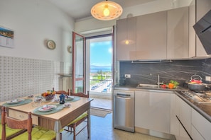 Een moderne keuken met een vaatwasser, een eettafel met stoelen en uitzicht op buiten.