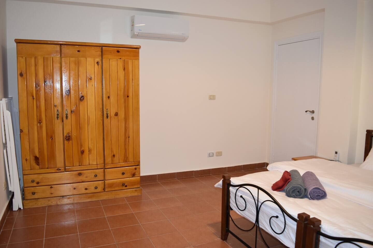 Ein Schlafzimmer mit einem Bett, einem Holzschrank und einer weißen Tür.