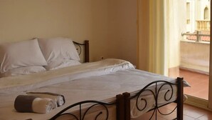 Ein Schlafzimmer mit einem Bett, einem Vorhangfenster und einem Balkon.