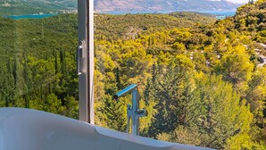 A bathroom with a bathtub and a large window offering a scenic view of a mountainous landscape. - Luxury Villa Morello Korcula 1 with Heated Pool (Korcula)