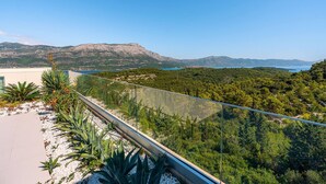 A balcony with a glass railing overlooking a mountainous landscape and a body of water. - Luxury Villa Morello Korcula 1 with Heated Pool (Korcula)
