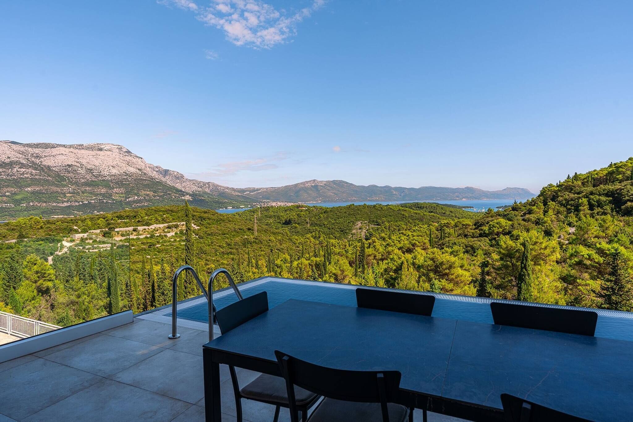Una piscina infinita con vistas a un paisaje montañoso y un lago.