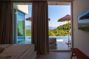 A bedroom with a large sliding glass door leading to a balcony with a pool and mountain view. - Luxury Villa Morello Korcula 2 with Heated Pool (Korcula)