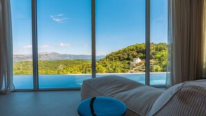 Una habitación con un ventanal que ofrece vistas a un lago y colinas.