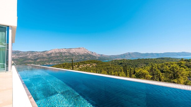 Una piscina infinita moderna con vistas despejadas a un paisaje montañoso.
