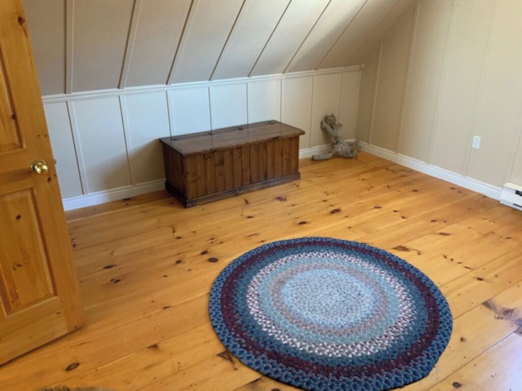 Ein Zimmer mit Holzboden, einer hölzernen Bank und einem runden Teppich.