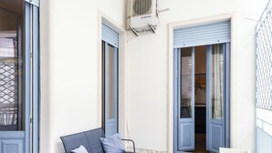 A modern apartment with a checkered floor, a sofa, a small table, and a window with blue shutters. - Agata Apartment with Balcony by Wonderful Italy (Catania)