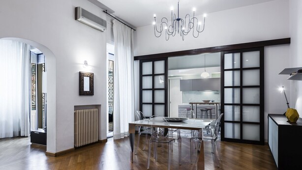 A modern kitchen with a central island, clear chairs, and a chandelier. - Agata Apartment with Balcony by Wonderful Italy (Catania)