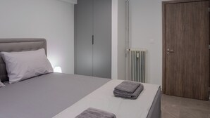 A bedroom with a bed, grey wardrobe, and a wooden door.