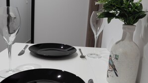 A dining table with black plates, silverware, and a vase with flowers.