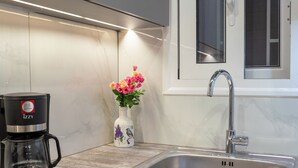 A modern kitchen with a built-in dishwasher, a coffee maker, a sink, and a window above the sink.