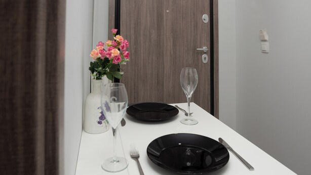 A dining table set with a vase of flowers, wine glasses, and cutlery.