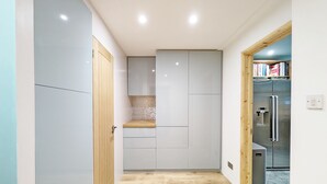 Une cuisine étroite avec des meubles gris, un plan de travail en bois et un réfrigérateur en acier inoxydable.