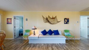 Un salon comprenant un canapé, deux fauteuils, une lampe et des œuvres d’art murales.