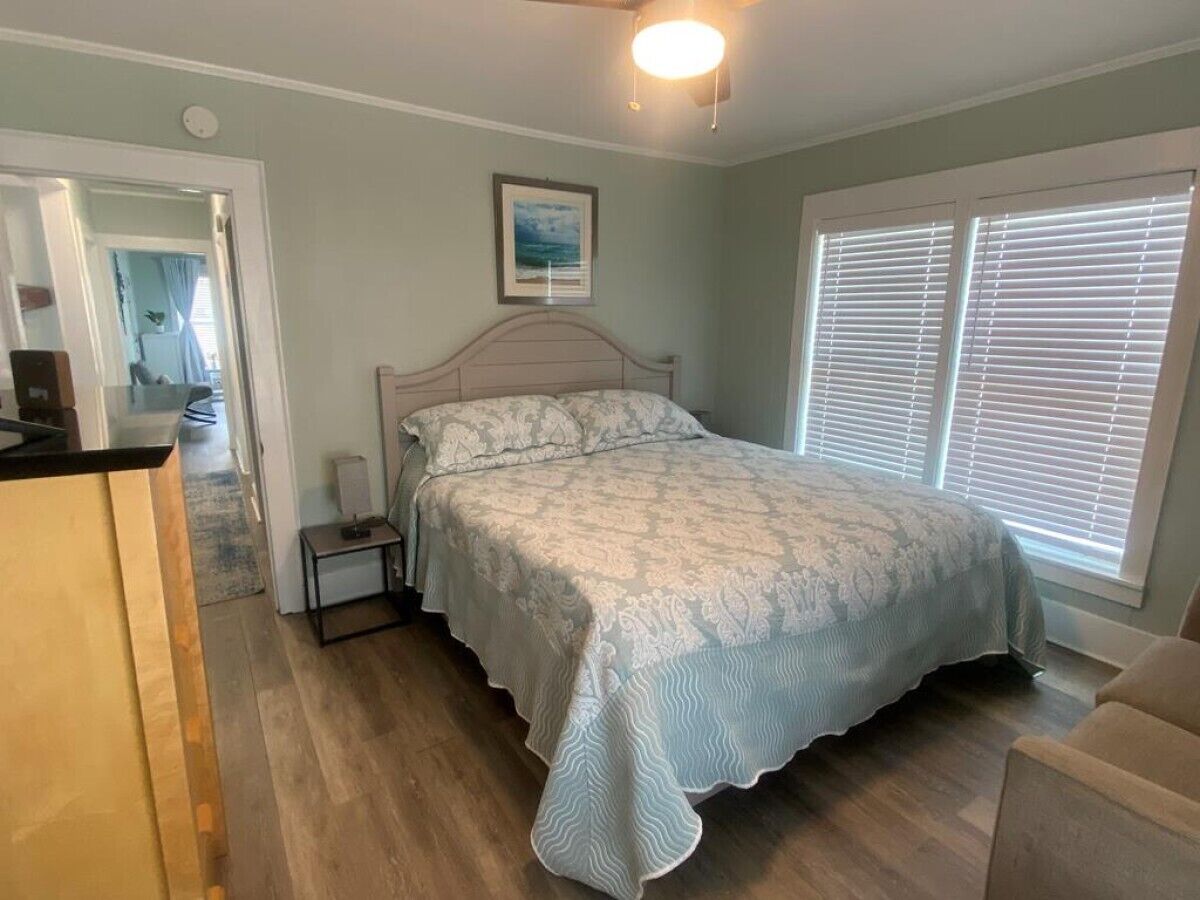 Une chambre à coucher avec un lit, une table de chevet et une fenêtre avec des stores.