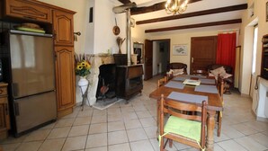 Una cocina con horno empotrado, una mesa de comedor con sillas, chimenea y una araña.