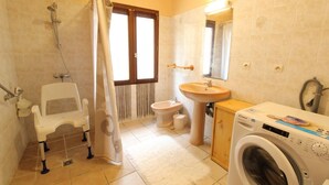 Un baño con ducha, inodoro, lavabo y lavadora.