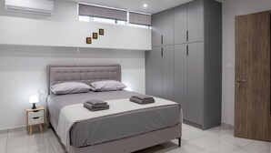 Un dormitori modern amb llit, taulella de nit, armari i emmagatzematge integrat.
