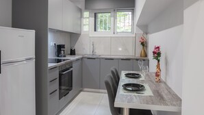 Una cuina moderna amb armaris grisos, forn integrat, cafetera i zona de dinar amb taula preparada per a dues persones.