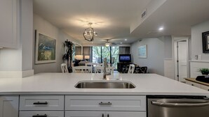 Una cocina moderna con una isla grande, electrodomésticos de acero inoxidable y un comedor con televisión.
