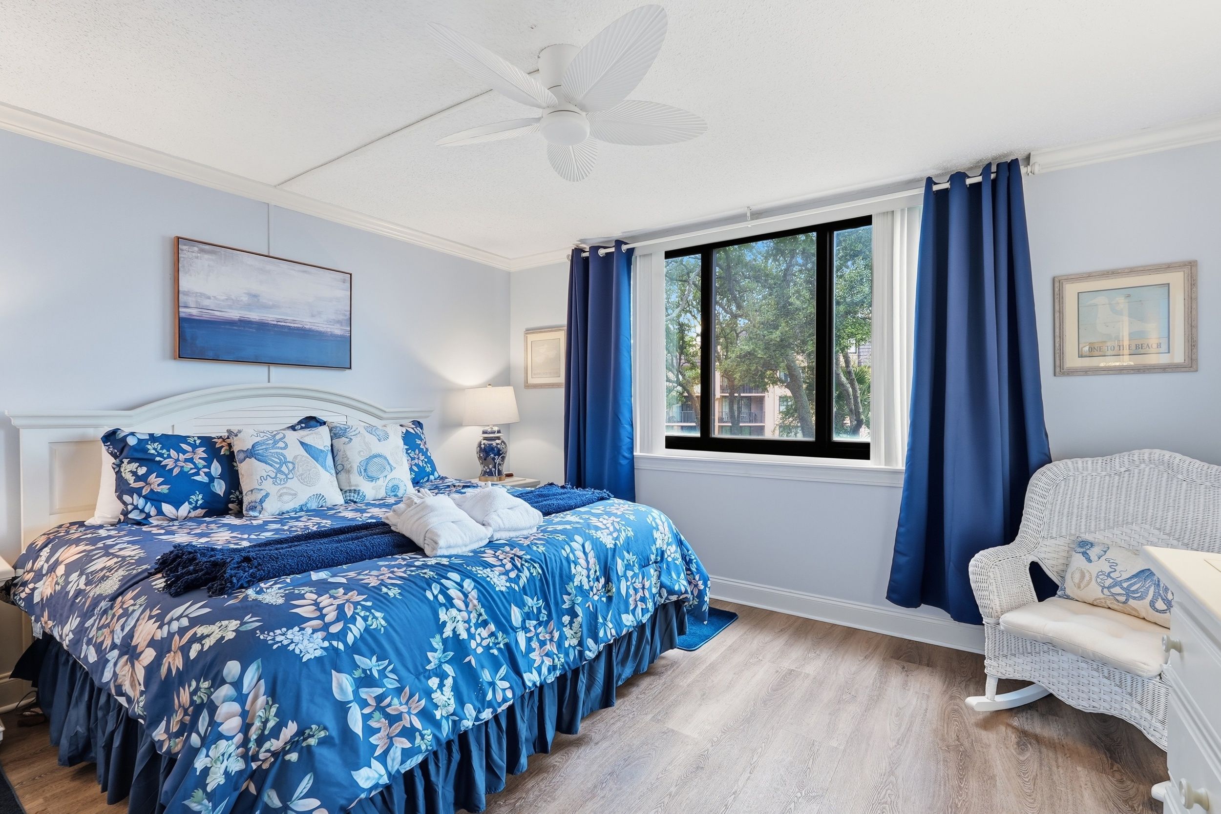 Ein Schlafzimmer mit einem Bett, einem Sessel, einem Fenster und einem Deckenventilator.