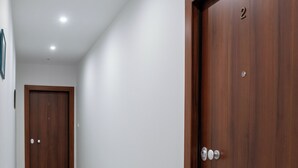 A hallway with two wooden doors, each marked with a number. The floor is tiled, and the walls are white. - Pagrati Studio New Chic and Central (Athens)