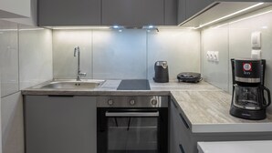 A modern kitchen with a built-in oven, a coffee maker, and a scale. - Pagrati Studio New Chic and Central (Athens)