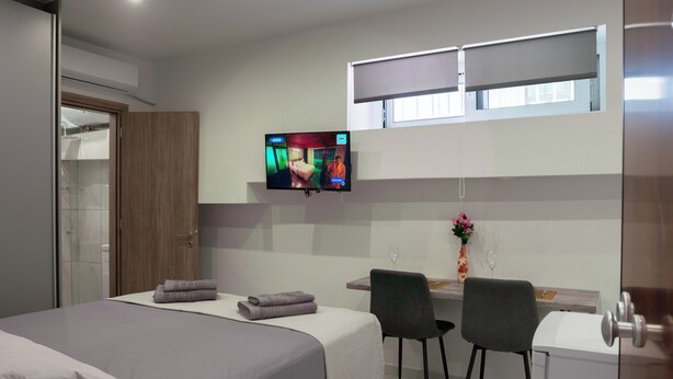 A hotel room with a bed, a desk, a chair, a TV, and a window. - Pagrati Studio New Chic and Central (Athens)