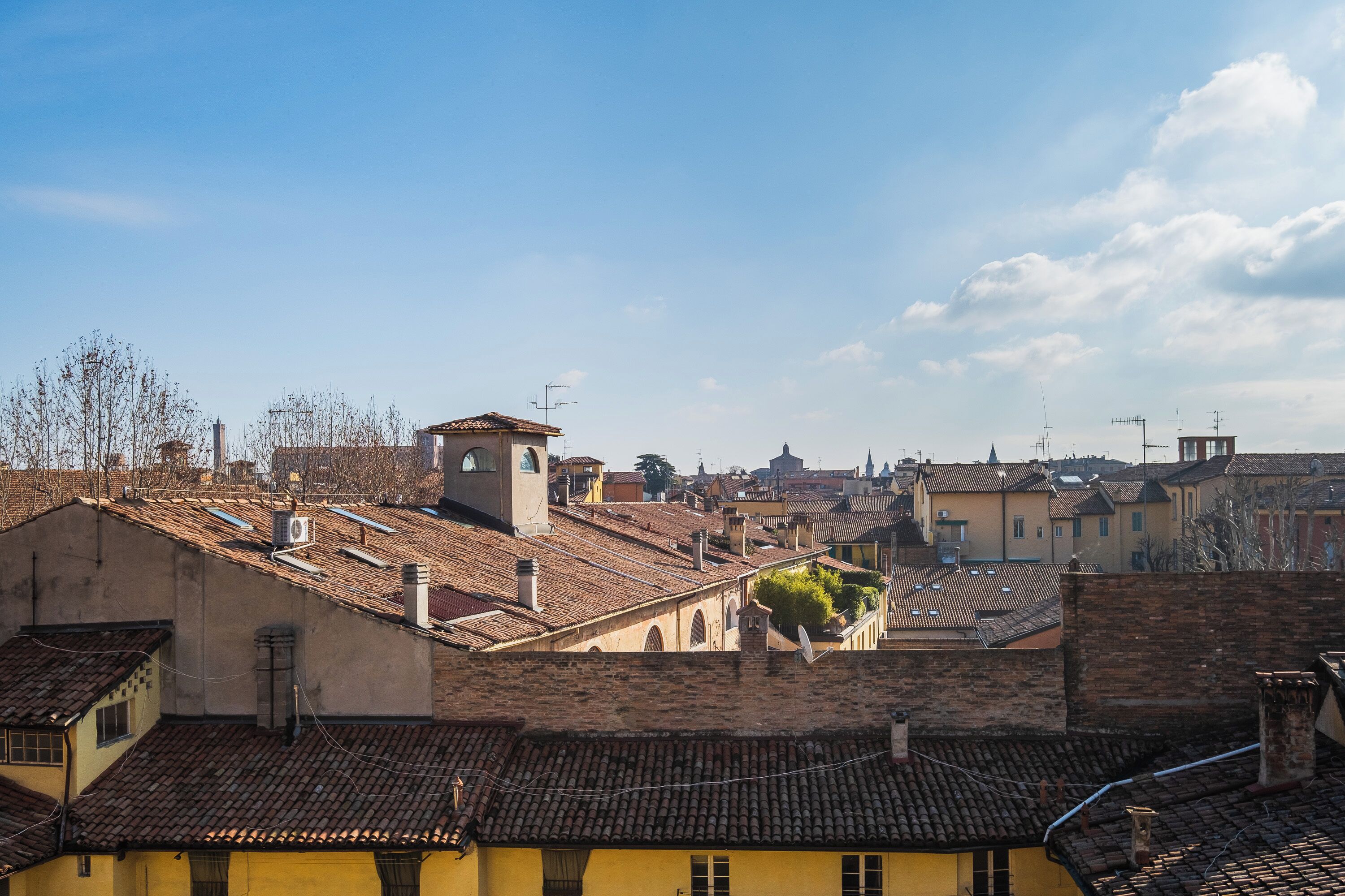A historic building with a clock tower, terracotta roof tiles, and a view of the surrounding cityscape.