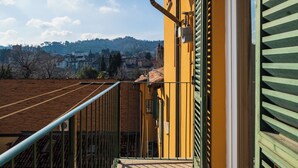 Een balkon met uitzicht op een heuvel en gebouwen in de verte.