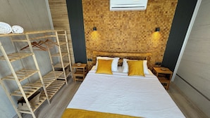 A neatly arranged room with a bed, a wooden shelf unit, and a small table.
