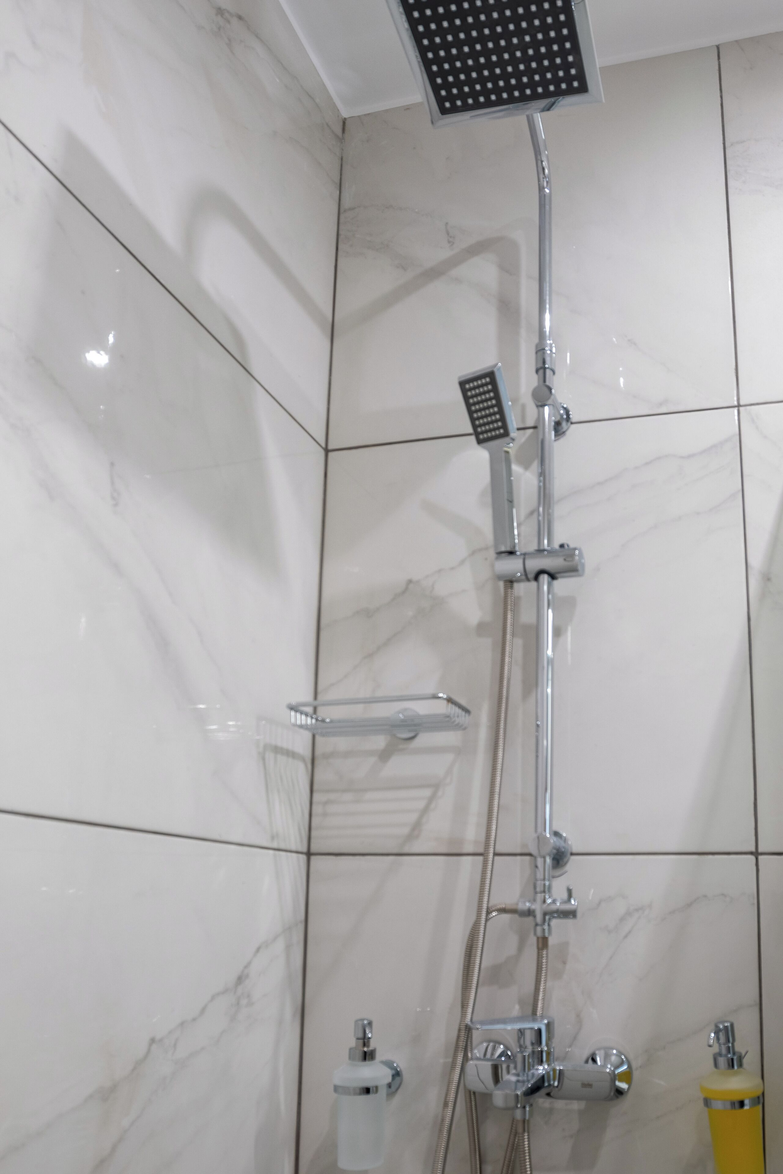 A modern bathroom with a shower, a towel rack, and a soap dispenser.