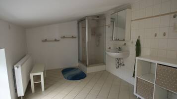 Ein Badezimmer mit Dusche, Waschbecken und einem kleinen Tisch.