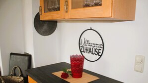 Eine Küchenarbeitsplatte mit einer roten Glasvase und einer Rose, einem gewebten Korb und einem Wandschild.