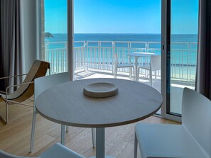 Enjoy ocean views from the large window in this stylish room, featuring a round table and two chairs.