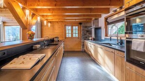 Une cuisine moderne avec des poutres en bois, un pare-feu en pierre et des appareils électroménagers en acier inoxydable.