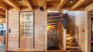 Un intérieur en bois avec une porte vitrée centrale, un mur en pierre et un escalier en bois.